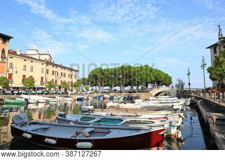 Desenzano, Italy - October 8:  The View Across Boats Moored In The Resort Town Of Desenzano To Cafes