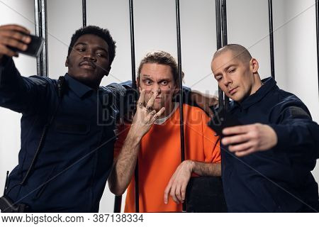 Warders In Full Gear Take Selfies On A Smartphone With A Dangerous Criminal Behind Bars. Black Guy A