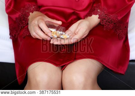 Woman Taking Pills, Bottle Of Capsules In Female Hands. Girl In Red Nightie On A Bed, Concept Of Sle