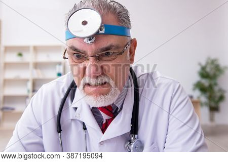Old male doctor otologist working in the clinic