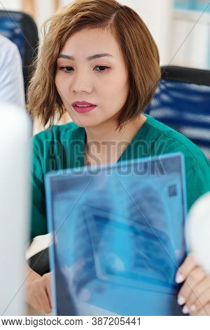 Young Asian Pulmonologist Examining Lungs X-ray Of Patient