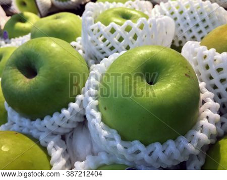 Pile Of Green Apple In The White Fruit Packaging foam Net. It Is The Round Fruit Which Typically Has