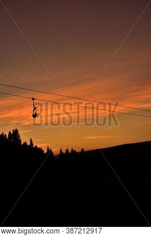 Ski Chair Lift In The Mountains At Red Sunset. Vertical Photo.