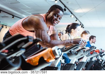 African man and friends exercising on fitness bike in gym
