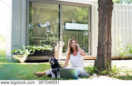 Mature Woman Working In Home Office Outdoors In Garden, Using Laptop.