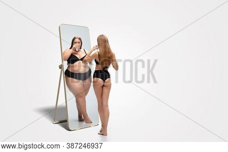 Young Fit, Slim Woman Looking At Fat Girl In Mirrors Reflection On White Background. Thinking Shes N