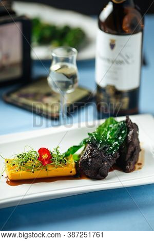 Spanish Veal Cheeks In Wine Sauce And Sweet Potato Puree With Wine Bottle On The Background