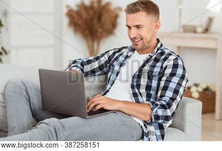Freelance And Remote Work Concept. Portrait Of Positive Man In Checkered Shirt Chatting Online Using