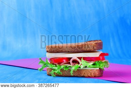 Multilayered Sandwich With Cheese, Pork Balyk, Bell Pepper, Lettuce Leaves And Toasted Bread Against