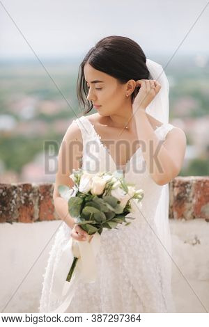 Beautiful Bride Stand In Frind Of City View With Bouquet And Smile