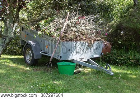 Trailer Full Of Garden Waste, Pitchfork And Bucket After Cleaning A Garden