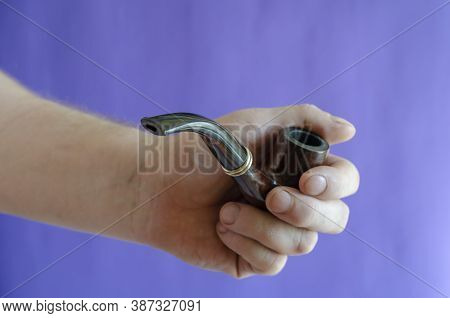 Briar Root Smoking Pipe In Hand. A Mans Hand Holds A Classic Smoking Pipe On A Blue Background. Sele