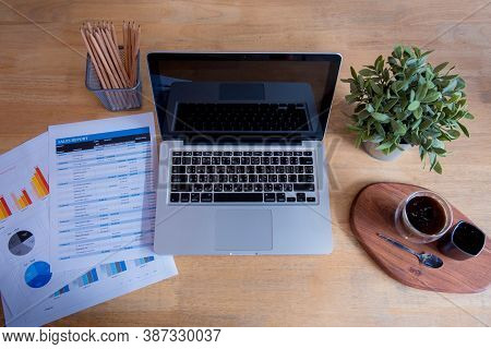 Office Laptop Business Financial Document Chart And Graph On Wooden Table With Coffee Cup. Flat Lay 