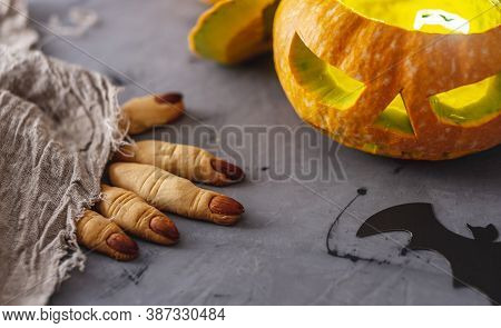 Pumpkin With A Face And Light Inside And Cookies Fingers Of A Witch For A Halloween Party On The Gra
