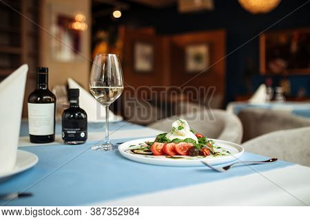 Restaurant Table Served With Gourmet Spanish Buratta Salad With Vegetables And Greens
