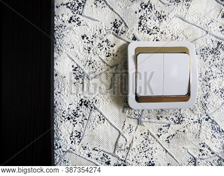 A White Light Switch With A Gold Border On The Wall And A Dark Text Insert On The Left. Home Electri