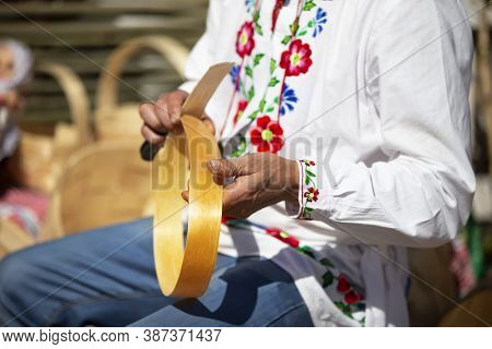 A Slavic Man In An Embroidered Shirt Makes Products From Birch Bark.