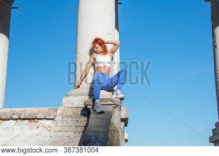 Red-haired Woman Athlete, Thirty-six Years Old, In Sports Leggings, Sits On The Street, Demonstratin