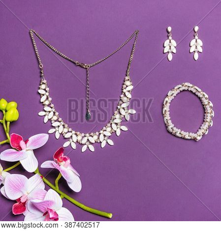Elegant Gold Necklace Bracelet And Earrings With Diamonds On Purple Background