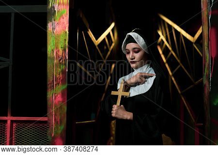 Scary Woman Devil Nun Holding A Cross. Horror Halloween Concept