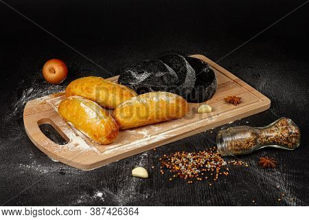 Fresh Wheat White Bread On A Cutting Board With Seasonings Sprinkled With Flour On A Black Wooden Ta