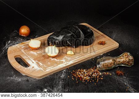 Fresh Black Rye And White Bread On A Cutting Board With Seasonings Sprinkled With Flour On A Black W
