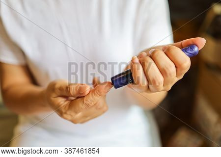Close Up Of Woman Hands Using Lancet On Finger To Check Blood Sugar Level By Glucose Meter. Use As M