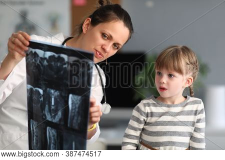 Woman Doctor Shows Child Patient An Xray In Clinic. Use Of Radiation Diagnostics Of Diseases Of Skel