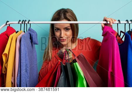 Blonde Woman Chooses The Clothes To Buy In A Store. Concept Of Shopping And Shopaholic.