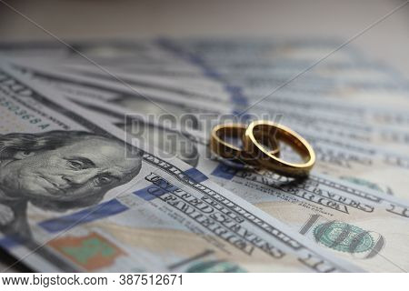 Wedding Rings On The Background Of 100 Dollars Bills. Marriage Conctract Or Prenuptial Agreement Con