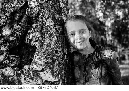 Teengirl sitting in the woods near birch. Black and white photo.