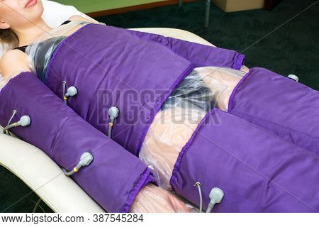 A Young Woman Lies In A Special Pressotherapy Suit For Slimming And Improving The Skin Of The Body.