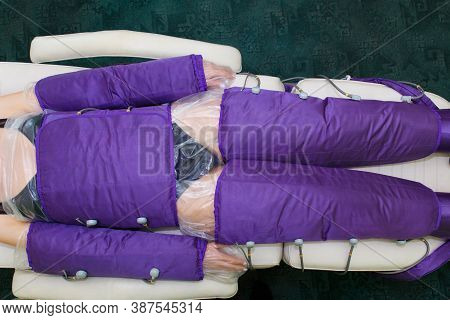 A Young Woman Lies In A Special Pressotherapy Suit For Slimming And Improving The Skin Of The Body.