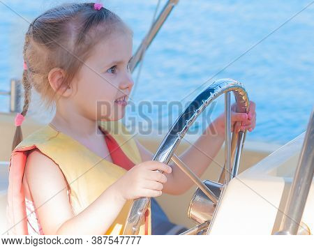Beautiful Three-year-old Girl At The Helm Of A Boat On A Clear Day