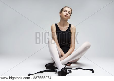 Portrait Of Professional Caucasian Ballet Dancer In Body Suit And Pointes Shoes Against White Backgr