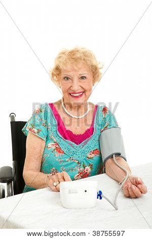 Starší žena si vlastní krevní tlak doma.  Izolované na bílém pozadí.