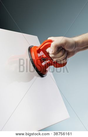 Człowiek podnoszenia białe płytki ceramiczne przy użyciu narzędzia przyssawki próżniowe aka dent puller.