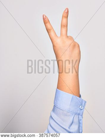 Hand of caucasian young woman doing victory symbol showing number two with streched fingers raised up over isolated white background