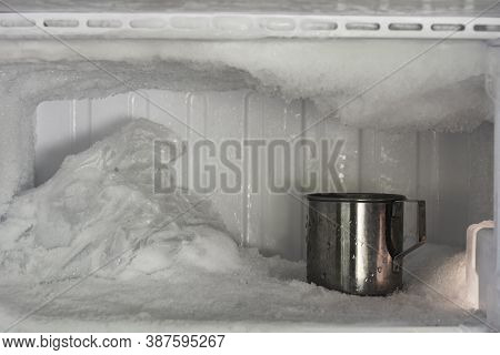 Stainless Steel Drinking Water Glass In Freezer Of A Refrigerator. Ice Buildup Inside Of A Freezer W