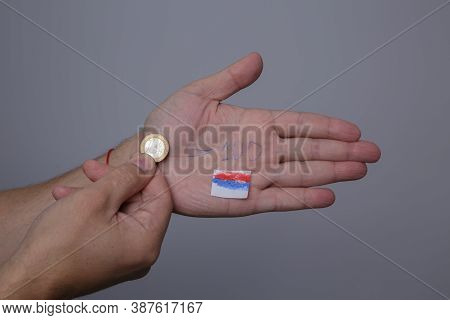 Man Hand Holds Euro Coin And On The Other Palm Course Of 100 Rubles Is Written