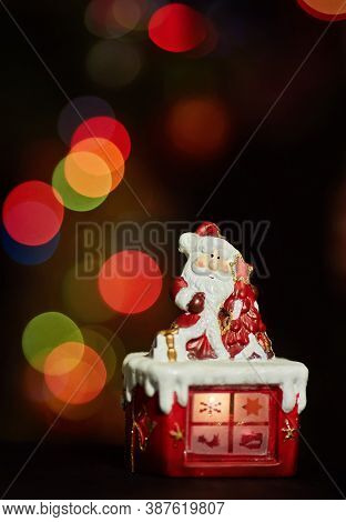 Santa Claus Statuette Doing An Exercise Waiting For Christmas. Colored Bokeh