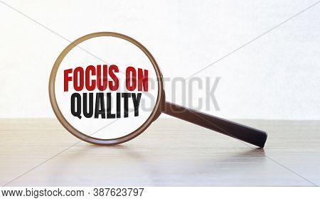 Magnifying Glass With Text Focus On Quality On Wooden Table.