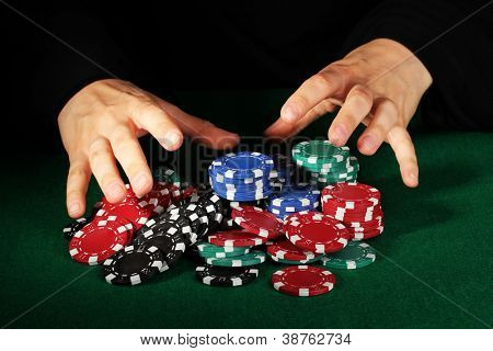 Poker fişleri ve yeşil masa üstündeki elleri
