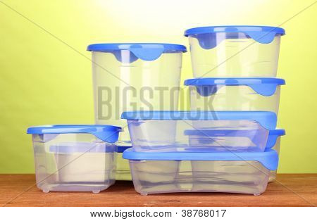 Contenants de plastique pour la nourriture sur la table en bois sur fond vert