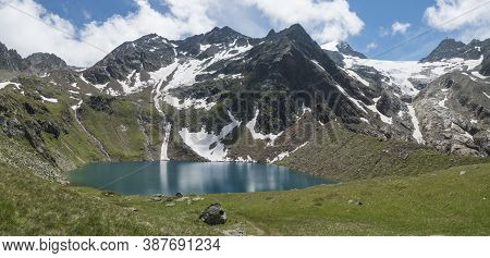Panoramic View Of Turquoise Blue Mountain Lake Grunausee In Alpine Landscape With Green Meadow And S