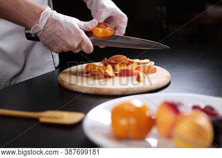 The Cook Cuts The Persimmons And Nectarines Into Slices. Assorted Fruits And Berries Are Cut Into Pi