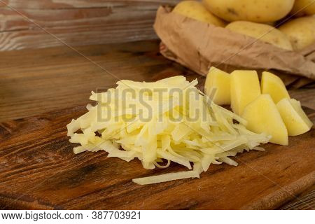 Raw Grated Potato On Wooden Cutting Board Background