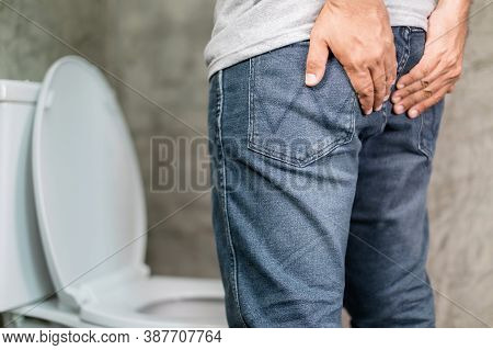 Close Up Man Standing And Holding On The Back Side In The Toilet. Concept Hemorrhoids