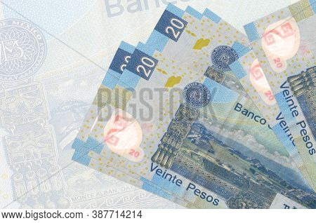 20 Mexican Pesos Bills Lies In Stack On Background Of Big Semi-transparent Banknote. Abstract Presen