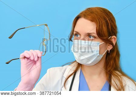Woman Nurse With Glasses On A Blue Background, Closeup Face.